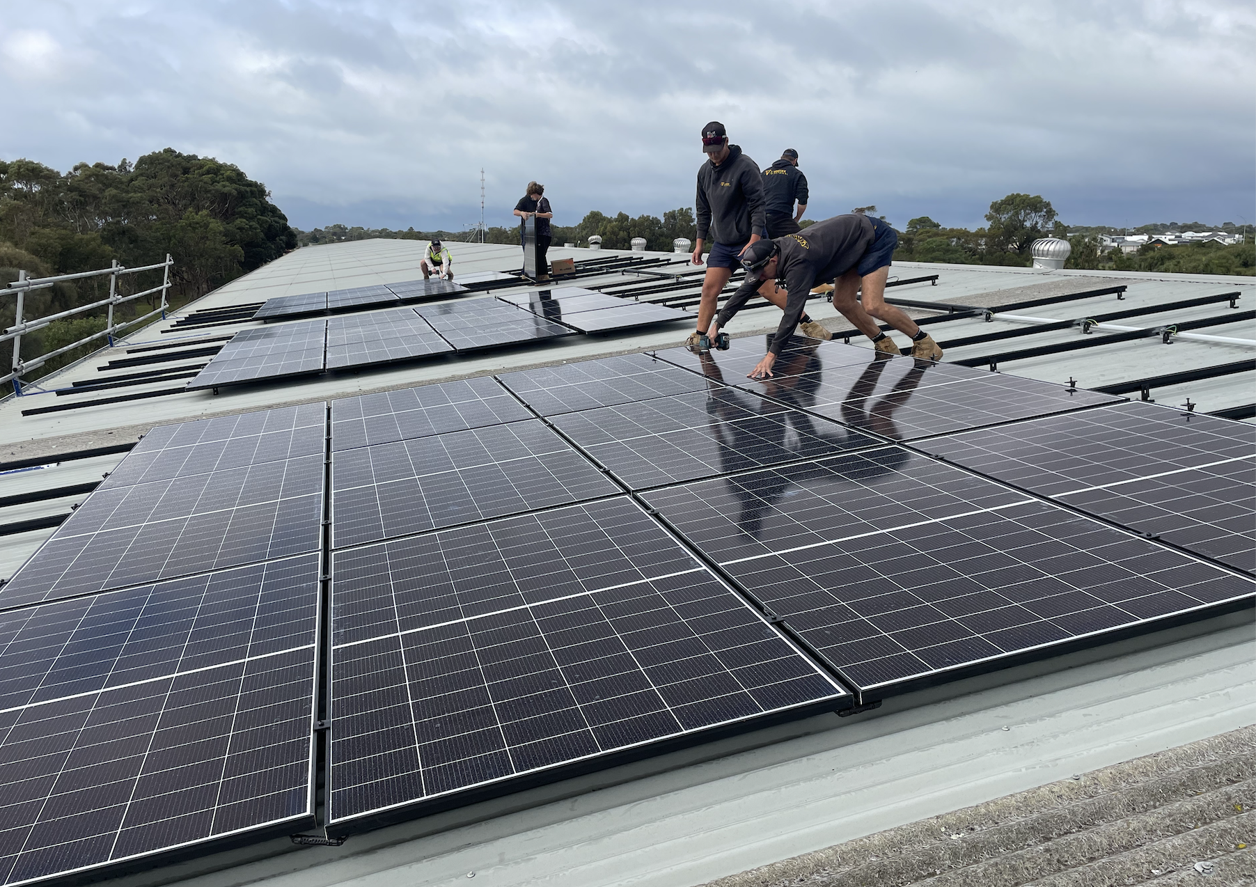Installers working on the solar panel array on the Lakers Siding shed roof